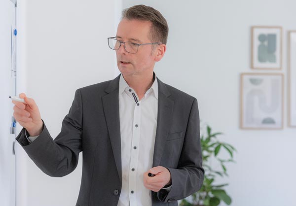 Dr. Peter Landgraf vor einem Whiteboard mit Stift