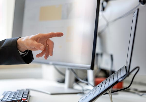 EIne Hand zeigt auf einen Computermonitor